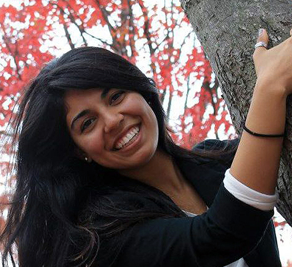 A woman stands with her arms crossed next to a window