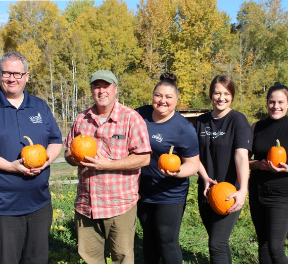 A group of people holding pumpkins and smiling